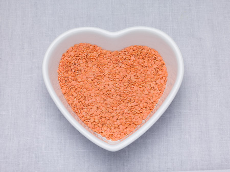 Red lentils, Petite crimson lentils in an oval bowl on a woven tablecloth backgroundの写真素材