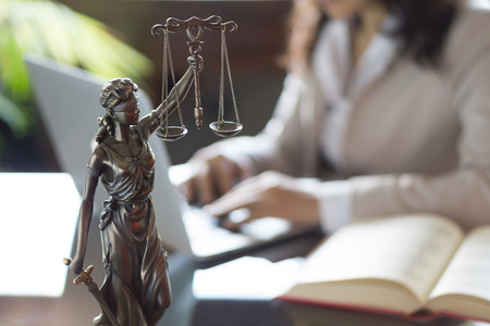 Lawyer office. Statue of Justice with scales and lawyer working on a laptop. Legal law, advice and justice conceptの写真素材