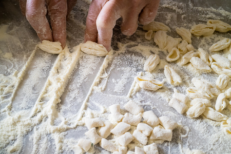 Hands of Italian woman making traditional fresh homemade pasta on a marble tableの写真素材
