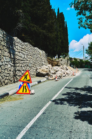 Repair of the supporting wall along the road. The fenced part of a crumbling stone wall on the road.の写真素材