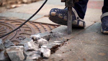 Working with a jackhammer on the slab. Legs of a worker with a jackhammer smashing a marble slab. 4k.の写真素材