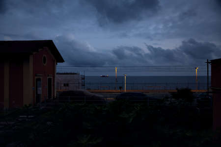 Railroad bordered by buildings by the sea at dusk
