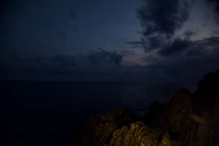 Sea at dusk with a cliff lit by a street lightの写真素材