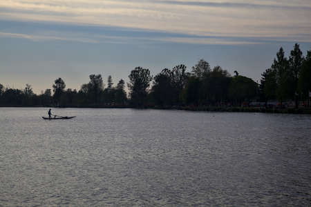 Man rowing on a boat on a lake at dusk
