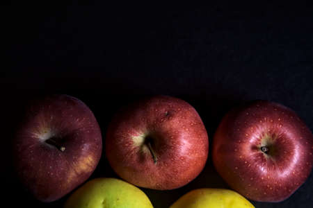 Red and yellow apples on a black background