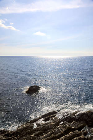 Rocks next to a cliff by the sea on a sunny dayの写真素材