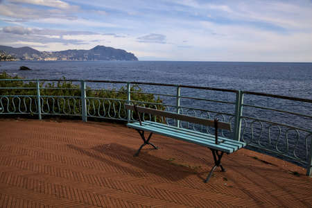 Bench on a panoramic trail by the sea on a sunny dayの写真素材