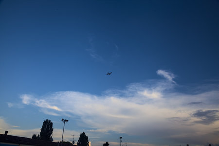 Sky framed by a roof top and an airplane in the distance