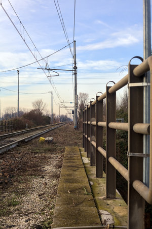 Railroad track bordered by bare trees that stretches to the horizon in the italian countryside in winterの写真素材