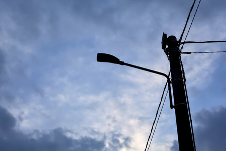 Street lamp on a concrete pylon with a cloudy sunset sky as backgroundの写真素材