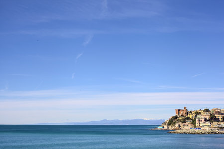 Cliff with historic buildings that stretches into the sea seen from the distance on a clear dayの写真素材
