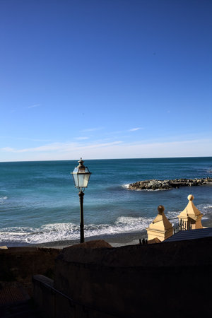 Sea and shore on a sunny day framed by a building seen from a balconyの写真素材