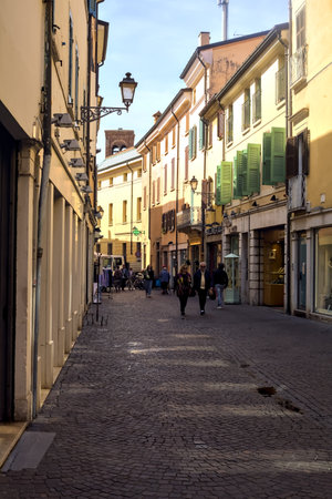 Narrow street in the shade with shops and people passing by on a sunny day in an italian townのeditorial素材