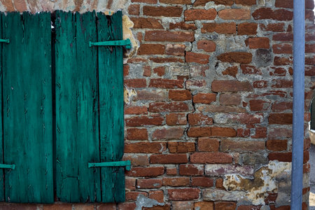 Brick wall and green shutters on a window in a facade seen up closeの写真素材