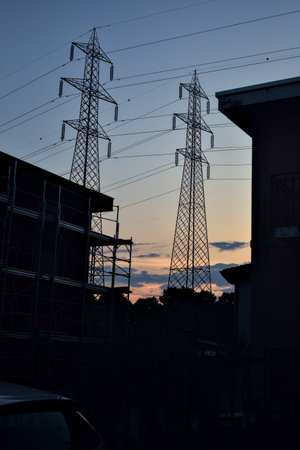 Electricity pylons at sunset framed by buildingsの写真素材