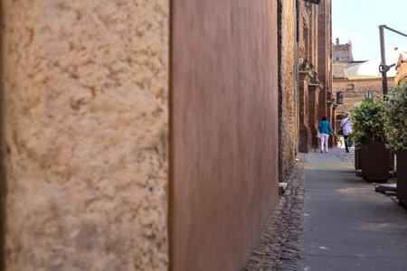 Alley partly in the shade with tables and chairs of a restaurant on a sunny day in an Italian townの写真素材