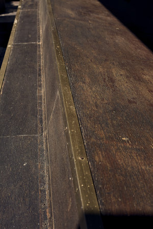 Wooden plank with a metallic border lit by the sun seen up close