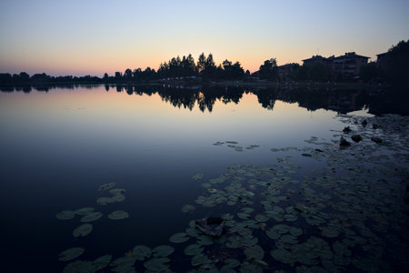 Riverside at sunset with its reflection cast in the water at sunset seen from afarの写真素材