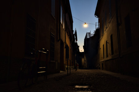 Narrow street with a hanging lamp above it in an Italian town at duskの写真素材