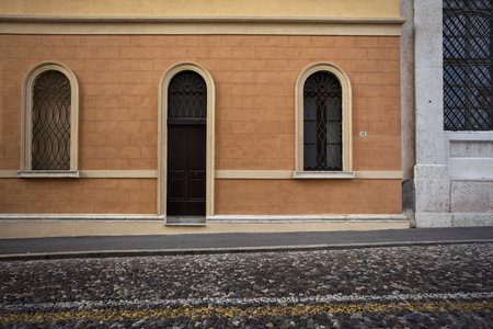 Wooden doors of buildings on a cobbled street in an italian town at sunsetの写真素材