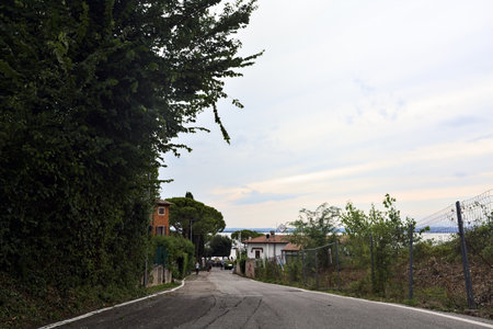 Road on a hill by the lakeside that leads to a resort on a cloudy sunsetの写真素材