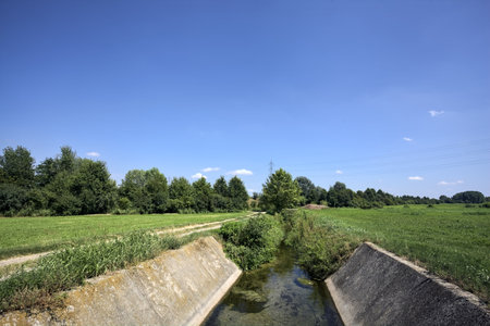 Trench with water between fields on a sunny day in the Italian countrysideの写真素材
