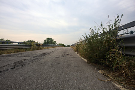 Bridge with pavements and railings at its edge on a cloudy day before rainfall in the Italian countrysideの写真素材