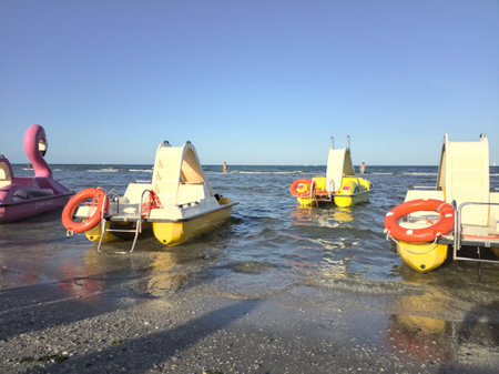 Pedalos floating on the water next to the foreshore at sunsetの写真素材