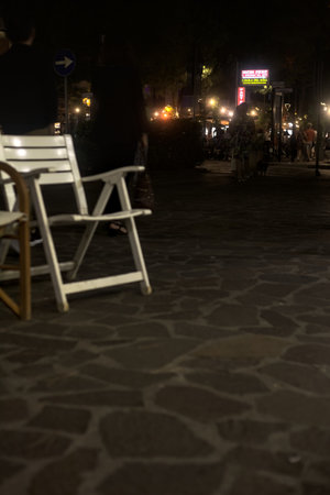 Empty chairs on the pavement of a boulevard in an Italian town by the seaside at nightの写真素材