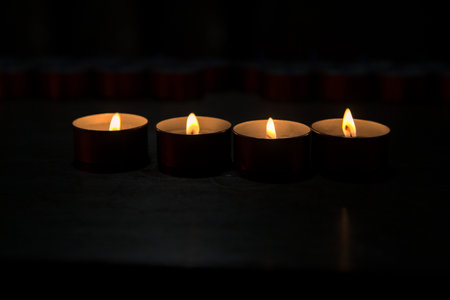 Rows of candles in the dark seen up closeの写真素材