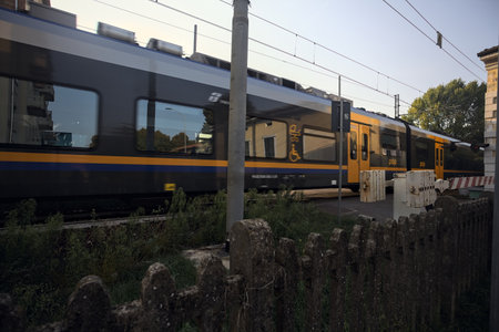 Mantua, Italy - October 2023 - Train passing on a railroad crossing at sunsetのeditorial素材