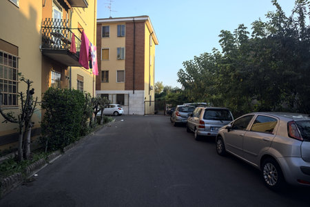 Mantua, Italy - October 2023 - Alley bordered by plants and parked cars next to a condominium at sunsetのeditorial素材