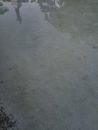 Tree tops and a statue in a park cast in the water of a fountain at sunsetの写真素材