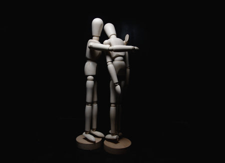 One wooden figurines comforting another oneの写真素材