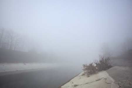 Concrete embankment of a diversionary channel on a foggy day in the Italian countrysideの写真素材