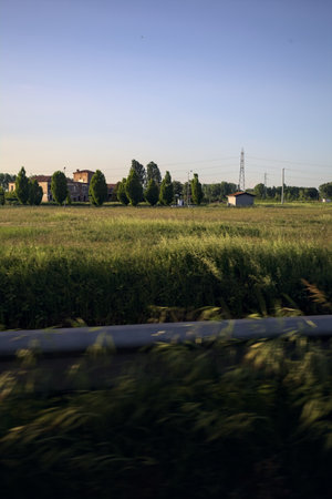 Field and rural manor next to a village in the Italian countryside at sunset seen from a roadの写真素材