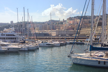 Pier with moored boats on a coastal city with its skyline and buildings of the harbor in the distanceの写真素材