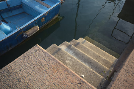 Stone stairs in a pier that goes into the water next to a boat