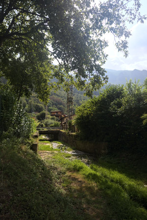 Dry creek bed passing under a bridge next to a pylon in the mountains on a sunny day