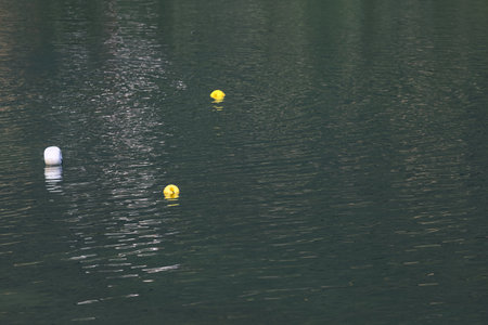 Buoys on a lake with their reflections cast on the waterの写真素材