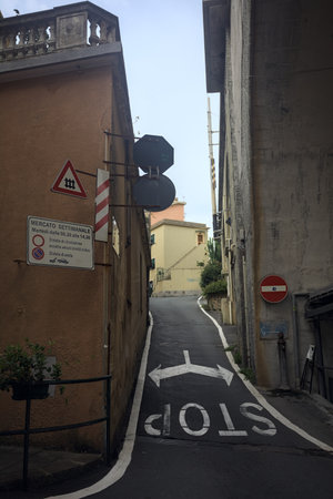Narrow alley on a slope next to a bridge with a stop sign on the groundの写真素材