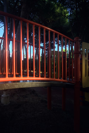 Footbridge in a playground of a park at sunset lit by the sunの写真素材