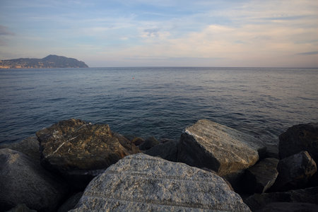 Sea stretching to the horizon at sunset seen from the rocks of a breakwaterの写真素材