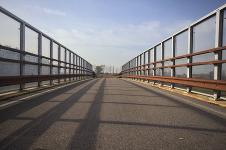 Paved bridge bordered by a barrier on a cloudy day in the Italian countryside