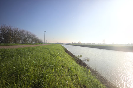 Diversionary channel bordered by trees and fields on a sunny day in the Italian countrysideの写真素材