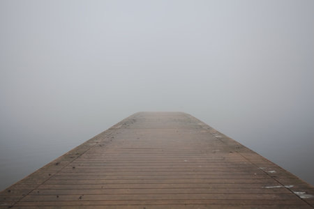 Pier stretching on a still lake in the fog in the morningの写真素材