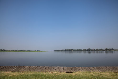 Clearing with grass by the lakeshore and opposite shores cast in the water