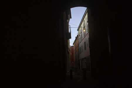 Alley in the shade passing under an archway of a building in an Italian town at sunsetの写真素材