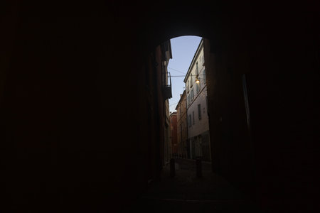Alley in the shade passing under an archway of a building in an Italian town at sunsetの写真素材