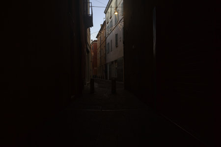 Alley in the shade passing under an archway of a building in an Italian town at sunsetの写真素材